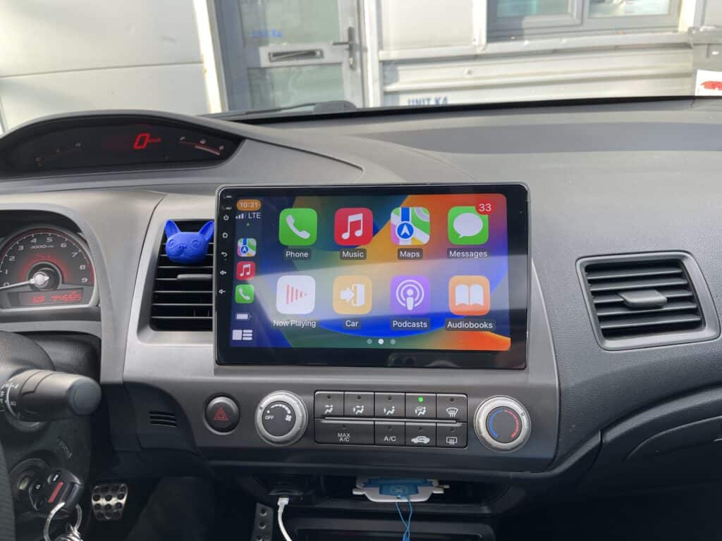 Touchscreen CarPlay system displaying Apple apps in a vehicle dashboard.