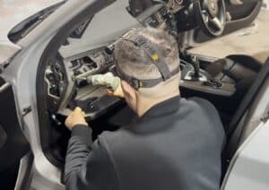 High-tech professional installing car radio system inside vehicle dashboard.