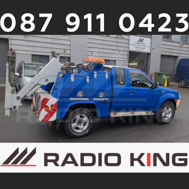 Blue tow truck equipped with lifting arm and compartments for roadside assistance.
