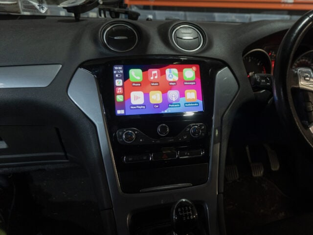 Android car stereo system with Apple CarPlay interface displayed on a vehicle dashboard.
