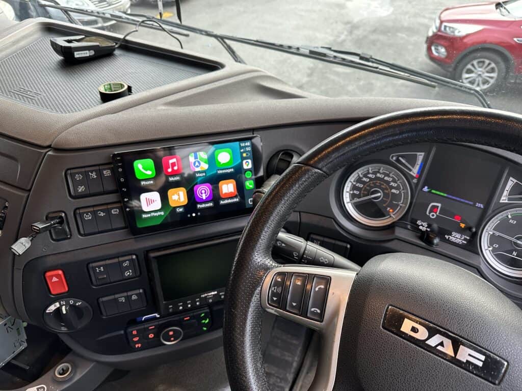 Digital Apple CarPlay screen on a truck dashboard with DAF steering wheel, showing various apps.